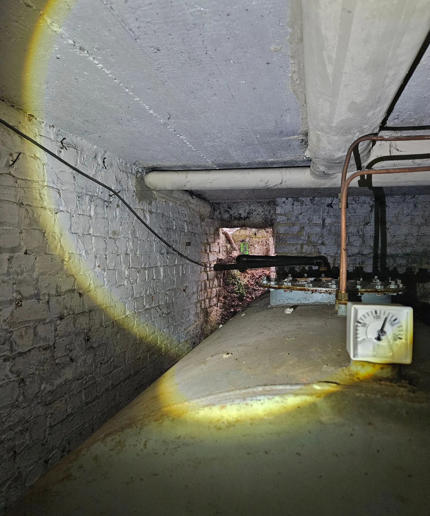 Stookolietank in een oude kelder met leidingen en manometer